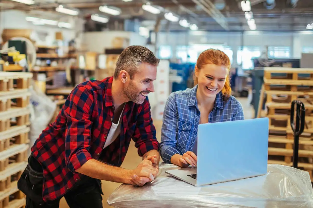 Two casually dressed freight professionals smiling as they look at information on their computer screen