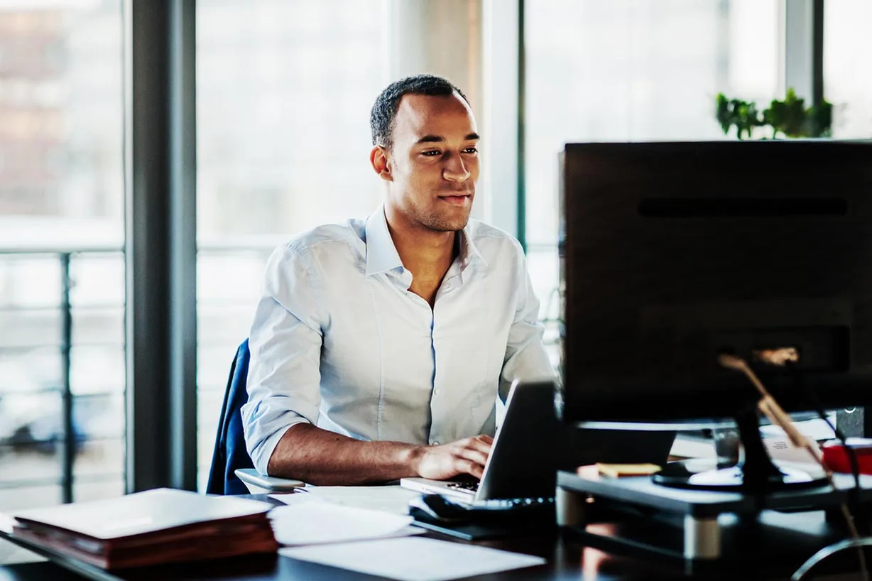 A freight tendering specialist looking at his computer with a slight smile